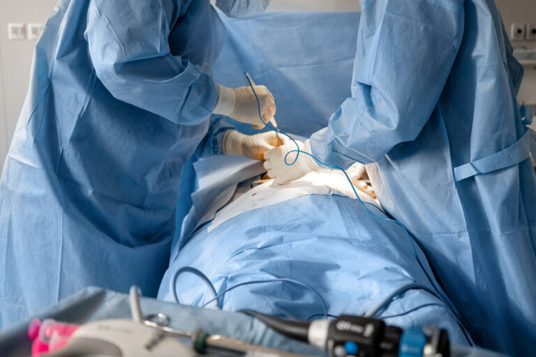 Two surgeons operates abdominal area of a patient